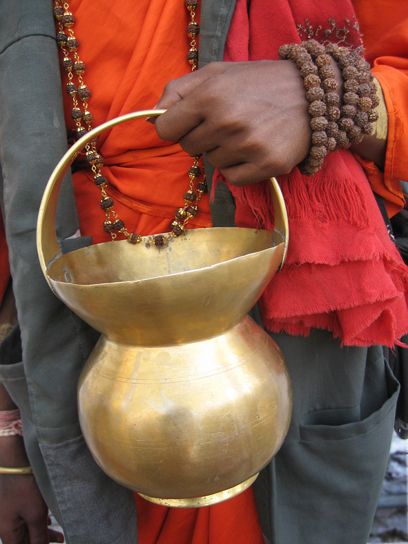 A sadhu holding a brass kamandalu
